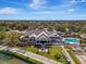 An aerial view of a luxurious clubhouse with a large pool, fire pit and meticulously maintained landscaping, near a golf course at 124 Ventana Way, Venice, FL 34292