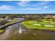 Scenic aerial view of a golf course with water features, sand traps and a meticulously maintained green, surrounded by lush greenery at 124 Ventana Way, Venice, FL 34292