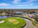 Overhead shot of a golf course and clubhouse, featuring a pond with a fountain, perfectly manicured greens and verdant landscaping at 124 Ventana Way, Venice, FL 34292