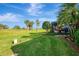 Lush green backyard featuring manicured landscaping, mature trees, palm trees, and a screened-in outdoor living area at 124 Ventana Way, Venice, FL 34292