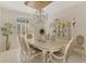 Dining room with a white dining set, elegant chandelier, and bright natural light at 124 Ventana Way, Venice, FL 34292