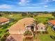 Beautiful aerial view of a home with a terracotta tile roof, two-car garage, and verdant golf course at 124 Ventana Way, Venice, FL 34292