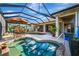 A luxurious screened-in pool area with a pool, hot tub, dining area, and view of home's exterior at 124 Ventana Way, Venice, FL 34292