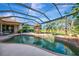 Beautiful screened-in pool area with a spillover feature, outdoor dining set, palm tree views, and lovely landscaping at 124 Ventana Way, Venice, FL 34292