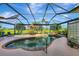 This backyard features a screened-in pool area, patio dining, lush landscaping, and views of the golf course at 124 Ventana Way, Venice, FL 34292