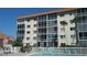 Beautiful condo exterior showcasing screened balconies, a pool area with lounge chairs, and well-maintained landscaping at 1600 1St W Ave # 304A, Bradenton, FL 34205