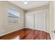Cozy bedroom featuring gleaming wood floors, a window with blinds, and a double door closet at 5383 Creekside Trl, Sarasota, FL 34243