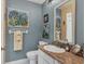 Charming bathroom with a granite countertop, white cabinetry and garden-themed artwork at 6420 13Th Avenue W Dr, Bradenton, FL 34209