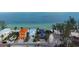 Aerial view of a two-story house with garages and colorful surrounding homes on a sandy beach at 915 N Shore Dr, Anna Maria, FL 34216