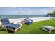 Relaxing backyard featuring manicured lawn, comfortable chairs, and stunning ocean views at 915 N Shore Dr, Anna Maria, FL 34216