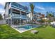 Spacious beachfront home with a large pool, outdoor dining area, and lush green lawn at 915 N Shore Dr, Anna Maria, FL 34216