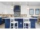 Stylish kitchen with white cabinets, dark blue island, pendant lighting, and modern appliances at 915 N Shore Dr, Anna Maria, FL 34216