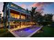Modern home features a sparkling pool, outdoor living spaces, and lush tropical landscaping at 915 N Shore Dr, Anna Maria, FL 34216