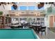 Game room with pool table, tables, seating, bookcase, and view to community pool at 3201 Beneva Rd # 204, Sarasota, FL 34232