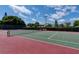 Outdoor tennis court with green and red surface, surrounded by lush trees and blue skies at 3201 Beneva Rd # 204, Sarasota, FL 34232
