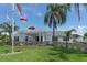 Elegant clubhouse exterior with manicured lawn, palm trees, flag pole, and covered entryway at 4741 Independence Dr, Bradenton, FL 34210