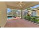 Screened-in patio with a brick floor, ceiling fan, and tranquil views of the pool and surrounding landscape at 4914 Lakescene Pl, Sarasota, FL 34243
