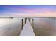 Long wooden dock stretches out into the water at sunset, creating a peaceful view at 7416 Riverview Dr, Bradenton, FL 34209