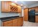 The kitchen has wooden cabinets, tiled floor, granite countertops and black appliances at 1001 Benjamin Franklin Dr # 110, Sarasota, FL 34236