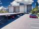 View of the condo building and covered parking lot with a row of parked cars under the shelter at 1001 Benjamin Franklin Dr # 110, Sarasota, FL 34236
