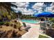 Relaxing pool area with lounge chairs, tables, and an umbrella with lush landscaping at 1001 Benjamin Franklin Dr # 110, Sarasota, FL 34236