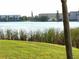 View of the lake and apartment buildings from across the grassy lawn with tree trunk on the side at 3756 Lake Bayshore # 509, Bradenton, FL 34205