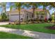 Charming single-story home features a lush landscaped yard with colorful plants and manicured green grass at 14614 Newtonmore Ln, Lakewood Ranch, FL 34202