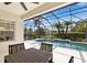 A screened-in pool area with outdoor dining space and a beautiful tropical landscape at 14614 Newtonmore Ln, Lakewood Ranch, FL 34202