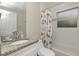 Bright bathroom featuring granite countertops, framed mirror, decorative shower curtain, and tiled tub with window at 330 Caruso Pl, Sarasota, FL 34237