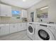 Well-lit laundry room featuring sleek cabinetry, granite countertops, and modern washer and dryer at 330 Caruso Pl, Sarasota, FL 34237
