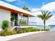 Modern building exterior with a waterfront view, palm trees and native plants in the foreground at 6821 Longboat S Dr, Longboat Key, FL 34228