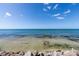 Serene ocean view with clear, shallow water over rocks and sand, under a blue sky with scattered clouds at 7314 Point Of Rocks Rd, Sarasota, FL 34242