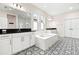 Bright bathroom with dual vanities, a soaking tub, and stylish black-and-white patterned tile floors at 1012 Fernleaf Run, Bradenton, FL 34212