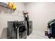 Laundry room with black washing machines, a wire rack for detergent, and tiled floors at 1012 Fernleaf Run, Bradenton, FL 34212