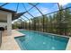 Inviting screened-in pool area featuring stone pavers, a grill, and lush backyard views at 1012 Fernleaf Run, Bradenton, FL 34212