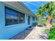 Charming exterior featuring a light blue painted house with a stepping stone walkway and beautiful tropical landscaping at 401 Shore Rd, Nokomis, FL 34275