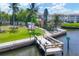 Scenic view of a private dock with lush landscaping and waterfront access, complete with an American flag at 4350 Chatham Dr # 208, Longboat Key, FL 34228