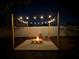The backyard fire pit is lit up at night and surrounded by chairs and strung lights at 5445 Bahia Vista St, Sarasota, FL 34232