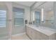An elegant bathroom featuring a vanity with a marble countertop, accent mirror, and walk-in shower at 8261 Grande Shores Dr, Sarasota, FL 34240