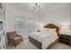 A bright bedroom with a tufted headboard, plush bedding, and a modern lighting fixture at 8261 Grande Shores Dr, Sarasota, FL 34240