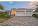 Charming single-story home featuring a three-car garage, paver driveway, and manicured landscaping for curb appeal at 8261 Grande Shores Dr, Sarasota, FL 34240
