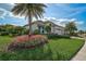 Lovely single-Gathering home with a green lawn, blossoming flowers, and stately palm trees at 8261 Grande Shores Dr, Sarasota, FL 34240