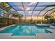 A screened-in pool with palm trees and a colorful sunset reflecting on the tranquil water at 8261 Grande Shores Dr, Sarasota, FL 34240