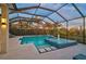 An inviting screened pool area with a fountain spa surrounded by lush landscaping and exterior lighting at 8261 Grande Shores Dr, Sarasota, FL 34240