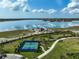 Aerial view of a well-maintained tennis court next to a beautiful lake in Lakehouse Cove at 8261 Grande Shores Dr, Sarasota, FL 34240
