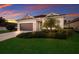 Beautiful one-story home with a lush green lawn, well-manicured landscaping and a sunset sky in the background at 176 Avens Dr, Nokomis, FL 34275