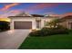 Beautiful one-story home with a lush green lawn, well-manicured landscaping and a sunset sky in the background at 176 Avens Dr, Nokomis, FL 34275