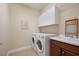 Functional laundry room equipped with a washer, dryer, cabinet, and sink for convenience at 176 Avens Dr, Nokomis, FL 34275