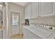 Bright laundry room with white washer and dryer, white cabinets and a door to the exterior at 5972 Giardino Ln, Sarasota, FL 34232
