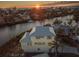 Aerial view of yellow two-story home with blue shutters near waterway at sunset at 114 Gull Dr, Anna Maria, FL 34216
